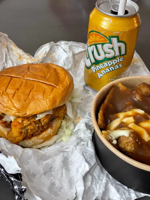 Buffalo Big Mary sandwich on the left, tater poutine with cheese curds on the right, can of Pineapple Crush in the top right