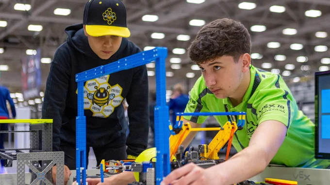 A volunteer checks the size of a VEX IQ robot.