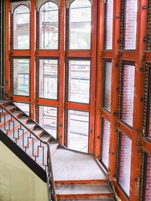 Partially demolished staircase with exposed beams and orange temporary wall framing around a stairwell windows.