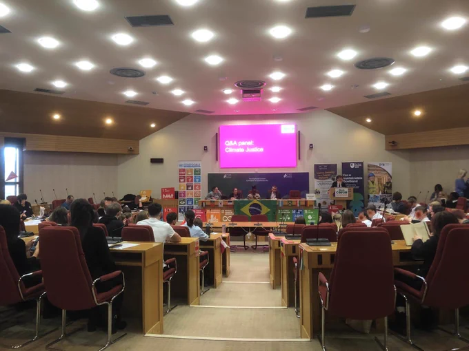 A group of people in a room, listening to a panel discussion on climate justice.
