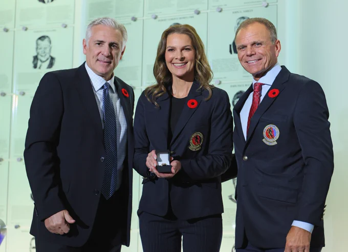 a photo of Seattle Kraken President of Hockey Operations Ron Francis, along with Mike Gartner, presenting Jennifer Botterill with her Hockey Hall of Fame induction ring.