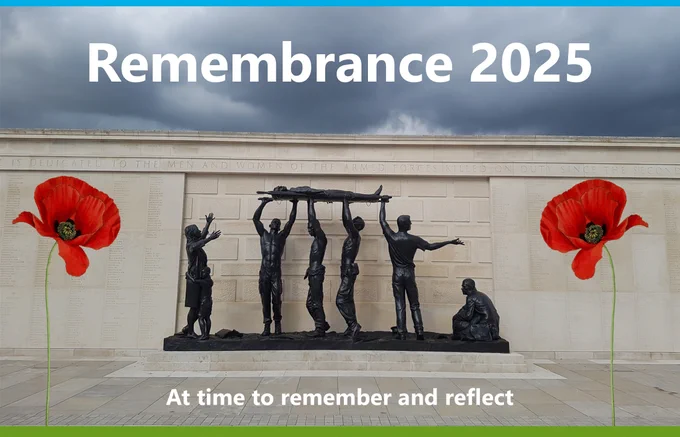A memorial scene with a bronze statue of servicemen lifting a stretcher in front of a stone remembrance wall. Large red poppies are placed on either side of the statue. The sky is grey and overcast. At the top, bold white text reads “Remembrance 2025,” and at the bottom, the message “A time to remember and reflect” is displayed.