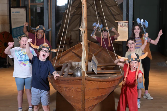 Kids at dig stood around a viking boat