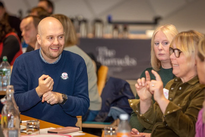 A man smiling while a woman talks