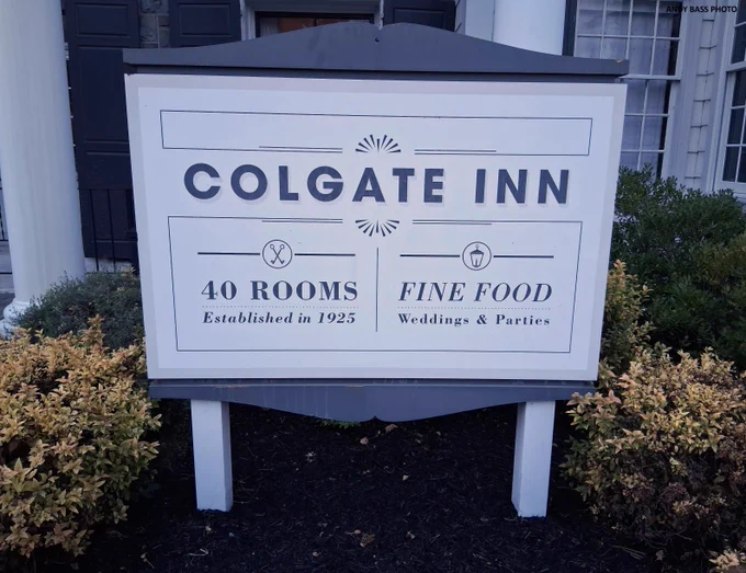 A metal sign stands outside the front entrance of the Colgate Inn in Hamilton, New York.  It was created by Charles Signs of Liverpool, New York.  (Andy Bass photo, 2025)