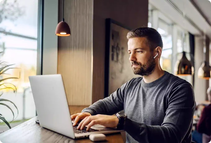 Man with laptop in café near window