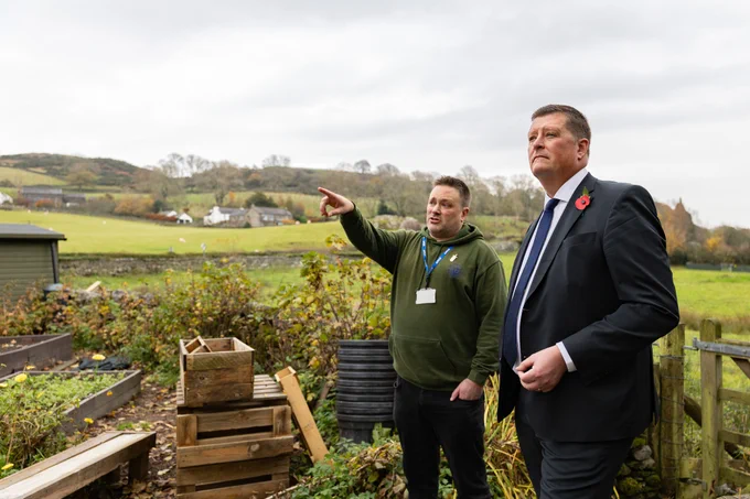 Headteacher in discussion with Sir Martyn Oliver, standing outside his school in the Lake District. 