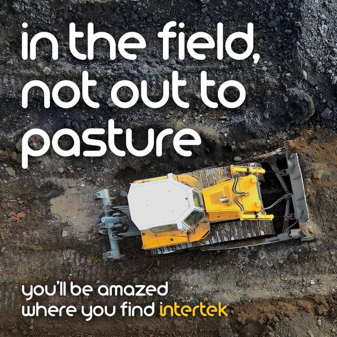 A large yellow machine working on a muddy field with the text "in the field, not out to pasture" and "you'll be amazed where you find Intertek."