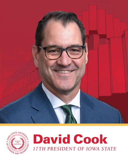 Professional headshot of David Cook. He is smiling and wearing a suit. The background is red with a faint image of the Innovation Center integrated into the design. A banner at the bottom displays the Iowa State University presidential seal and bold text that reads “David Cook,” with “17th president of Iowa State University” underneath.
