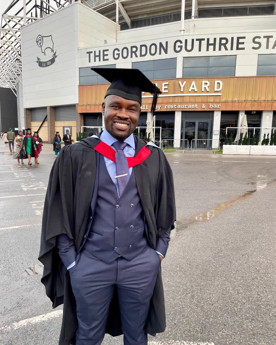 A smiling man is celebrating graduation day at Pride Park Stadium 