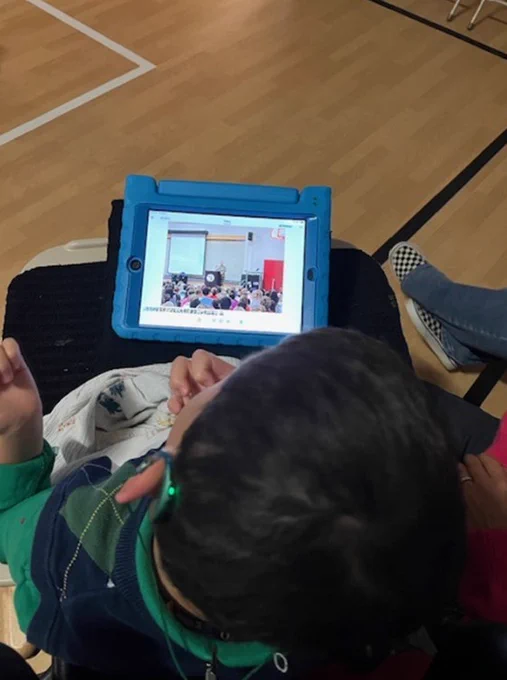 boy looking at a picture of a veteran's day speaker on his iPad.