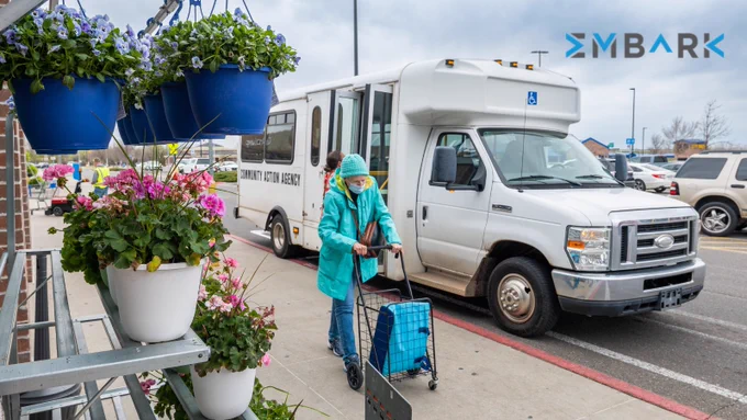 Senior citizen using EMBARK services, pushing cart outdoors, in front of a grocery store.