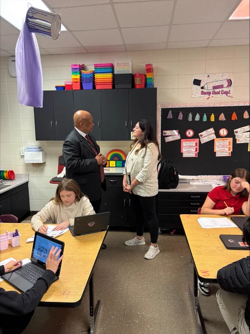 Dr. Yearwood talking with a teacher in a classroom.