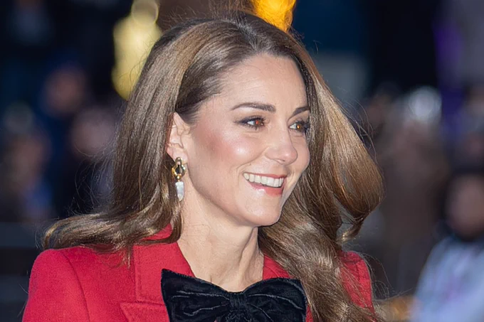 The Princess of Wales, wearing a red coat with a black velvet bow, smiles as she arrives outside Westminster Abbey for a service