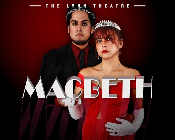 Two students in red formal wear and crowns pose together, unsmiling, their gazes formidable.