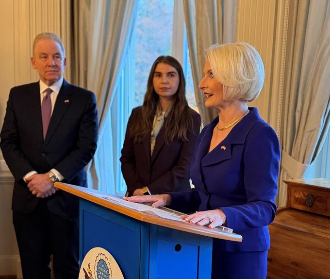 Ambassador Callista L. Gingrich speaks at a podium with Robert J. Giuffra Jr. nearby.