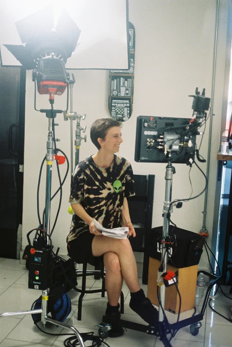 Julia sitting on a stool near the monitor, smiling 