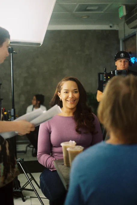 Our lead, Jaiden, seated at a cafe, smiling at her co-star 