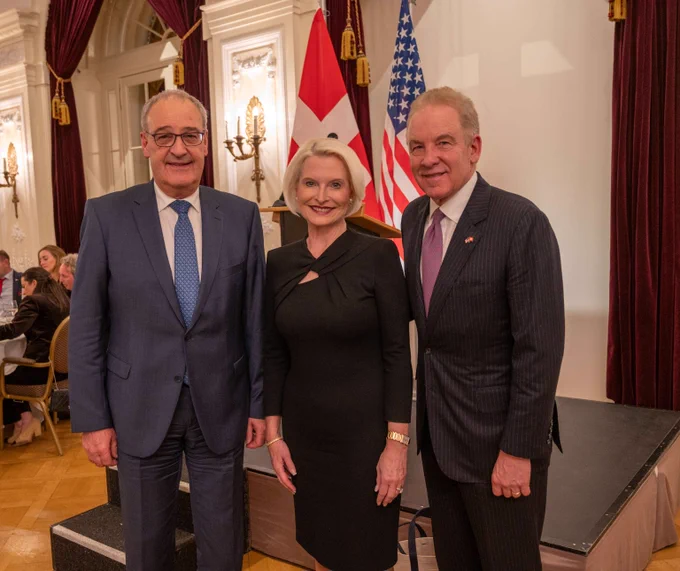 Ambassador Callista L. Gingrich poses for a photo with Vice President Guy Parmelin and American Swiss Foundation Chair Robert J. Giuffra Jr. with the U.S. and Swiss flags in the background.
