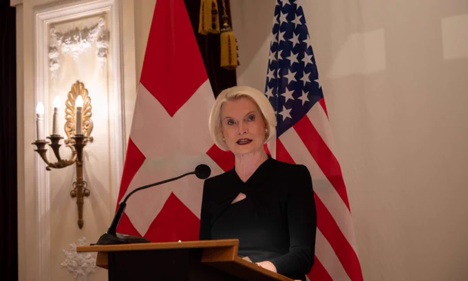 Ambassador Callista L. Gingrich delivers remarks at a podium with the U.S. and Swiss flags in the background.