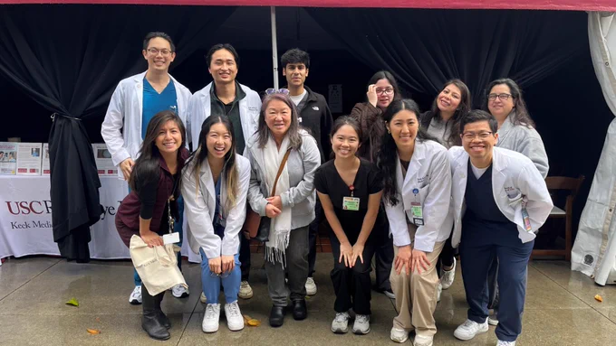 Group of individuals from the Roski Eye Institute and Department of Ophthalmology posing together at their booth at the 2025 LA Festival of Books.