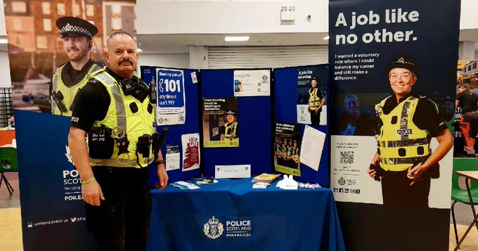 Police Officer standing in front of Police stand with information.