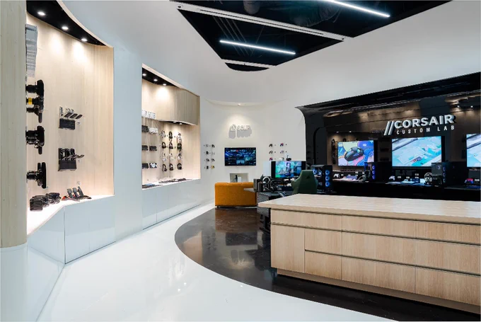 Interior of a Corsair retail store showcasing various electronic products, gaming setups, and a reception desk, with modern lighting and design.