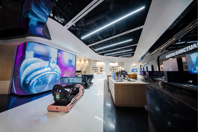 Interior of the CORSAIR Experience Store, featuring a FANATEC Simulator Setup, large curved digital displays with vibrant imagery, and various tech products. 