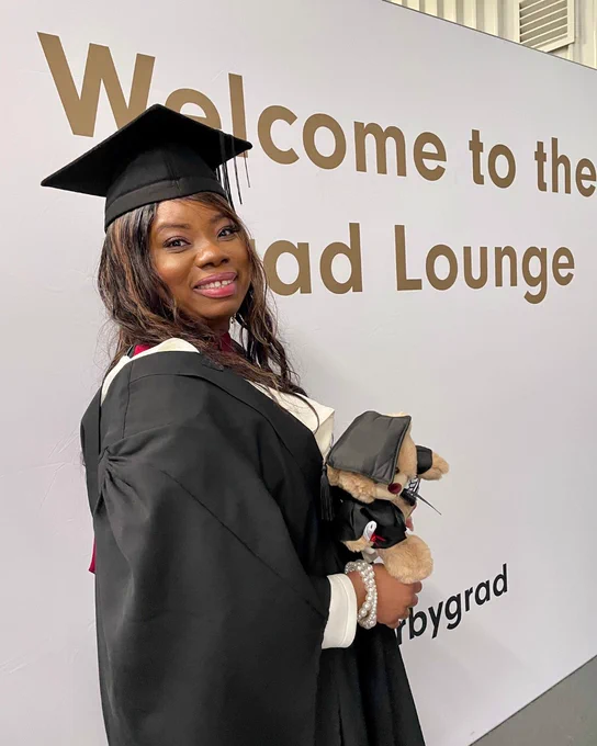 A graduate holds a teddy bear at the University of Derby ceremonies