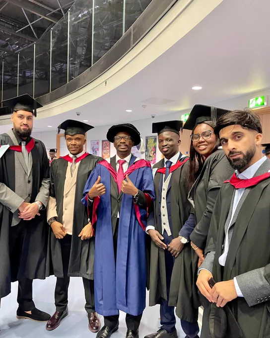 A large group of friends smile during the University of Derby graduation ceremony