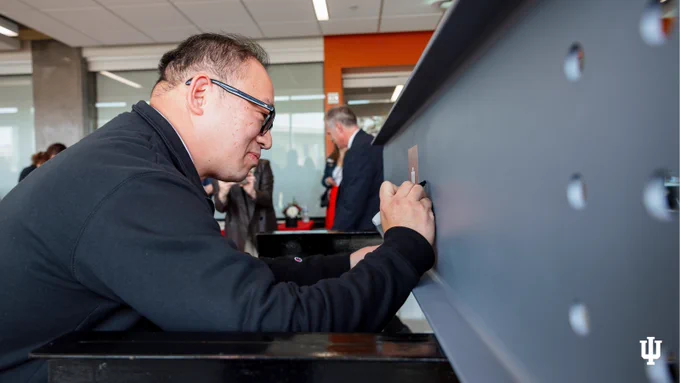 An individual is using a touchscreen device at a facility marked with the Indiana University logo.