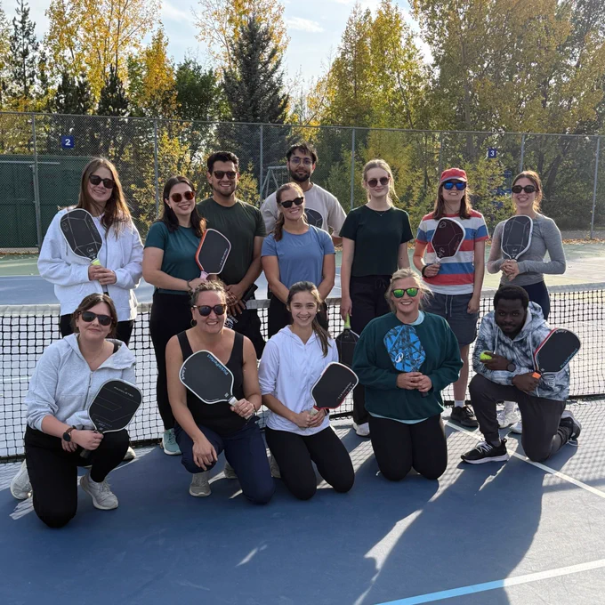 The ENHANCE lab team poses for a group photo on a pickleball court after learning to play the game together.