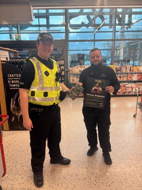 police officer standing with retail staff at Silverburn.  Both holding retail crime prevention posters