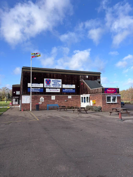 The Bedfordshire flag raised above Biggleswade rugby club.
The flag's yellow and red quadrants are taken from the arms of the Beauchamp family, powerful in the county after the Norman conquest of England and constructors of Bedford Castle. The blue and white wavy lines symbolise the Great Ouse, which flows through the county. The three shells are taken from the coat of arms of the Duke of Bedford.
