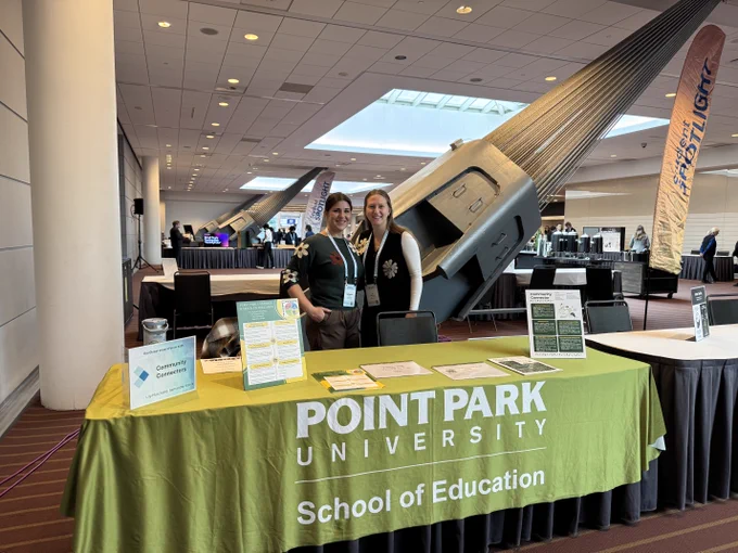 Two individuals standing behind a booth that displays "Point Park University School of Education" at a conference hall, with a banner and promotional materials on the table.

Samantha Stanis (L) and Lily Marchand (R) demonstrated technology-based strategies for English Language Learners at The Global Impact Forum. Submitted photo.