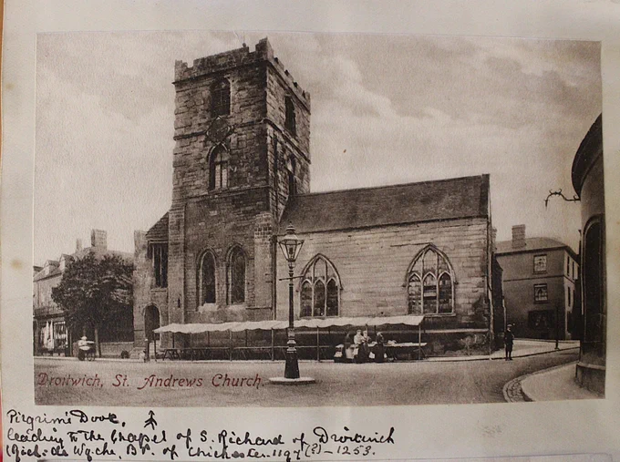 A parish church with a market stall set up in the street in front of it.