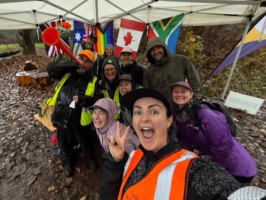 Group of parkrunners in Canada smiling under a tent with international flags on a rainy day.