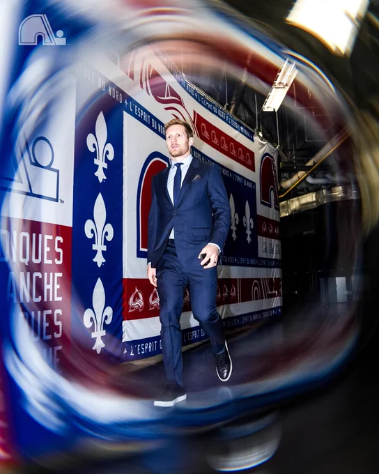 Gabriel Landeskog in a full navy suit with a light blue shirt, a blue tie and black shoes.