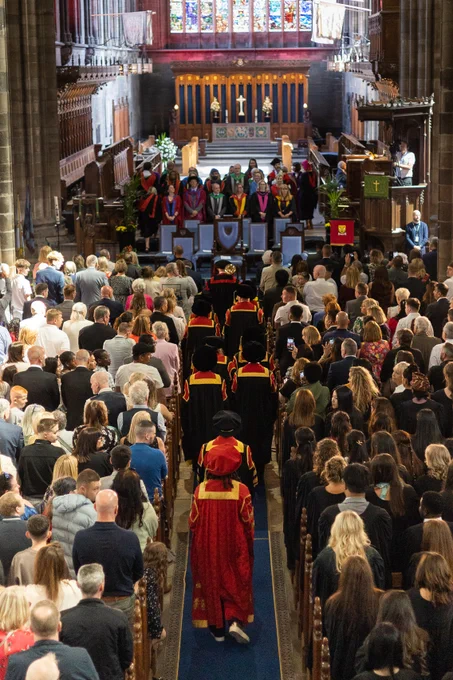 Graduation ceremony inside Paisley Abbey, with attendees in formal attire and academic robes, walking down the aisle.