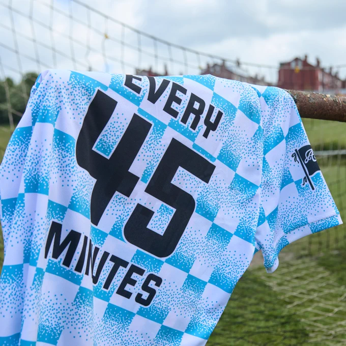 A Prostate United shirt hanging on a goal net, featuring a blue and white pattern with the text ‘EVERY 45 MINUTES’ displayed prominently.