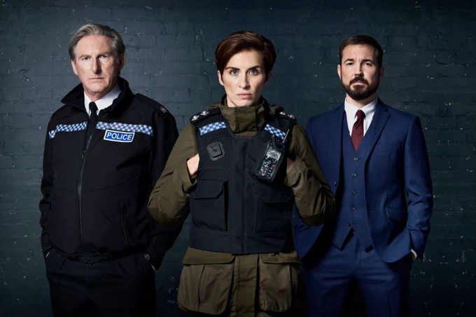 Adrian Dunbar as Ted Hastings, Vicky McClure as Kate Fleming and Martin Compston as Steve Arnott standing in a line, wearing police clothing, looking serious at the camera.