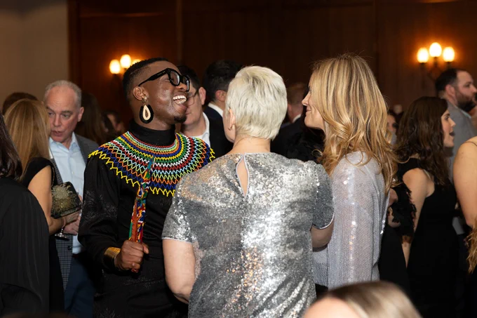 People in formal attire laugh while in conversation