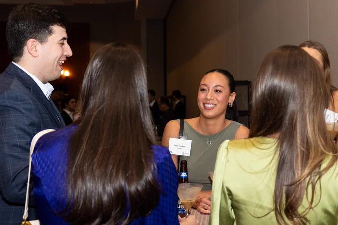 People in formal attire smile while in conversation