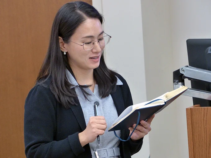 Seulki Lee-Geiller consults her notes as she speaks in a classroom.