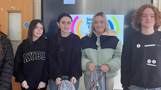 Four young people in front of a screen.