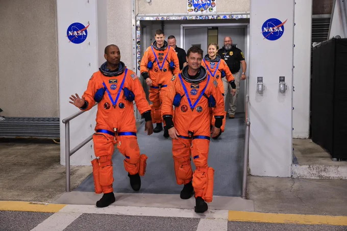 The crew of Artemis II (top left to bottom right: Victor Glover, Reid Wiseman, Jeremy Hansen, and Christina Koch) walking out of the Neil A. Armstrong Operations and Checkout Building at NASA’s Kennedy Space Center. They are wearing the bright orange Artemis suits. Credit: NASA/Kim Shiflett