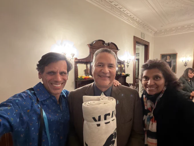 Selfie of Dr. Rao and his wife, Monica, with a gentleman between them who is holding a large roll of fabric with V-C-U's logo on it.