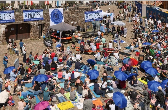 LiegendDemo am 10.05.25, Menschen am Boden sitzend,  teilweise mit blauen MECFS Schirmen