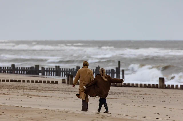 Two people walking along a beach