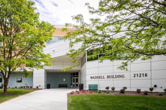 A picture of an academic building at the NOVA Loudoun campus, with trees framing a path.